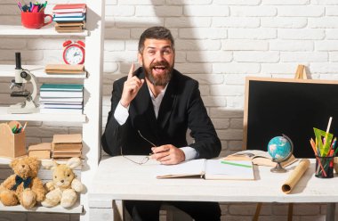 Anaokulundan ya da ilkokuldan erkek öğretmen portresi. Öğretmenin bir fikri var. Öğrencileri bekleyen hayret verici öğretmen, özgüvenle gülümsüyor. Pozitif ifade duyguları komik yüz