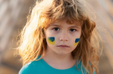 Savaş yok, savaşı durdurun, Rus saldırısını durdurun. Çocukların yanağında Ukrayna bayrağı. Çocuklar yüzünüzü kapatın.