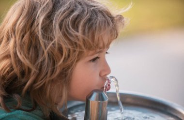 Parktaki bir çeşmeden su içen çocuk.