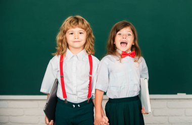 Okula dönelim. Öğrenci arkadaşlar bilgi gününde okula dönüyorlar. En iyi okul arkadaşları tahtanın yanında el ele tutuşuyorlar.