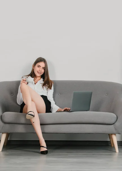 Beautiful secretary. Sexy businesswoman in with sexy legs. Seductive woman with laptop, sensual secretary sit on sofa in office
