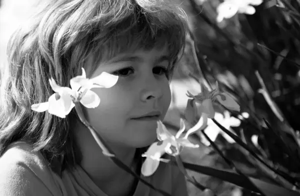 Flower allergy. Spring park. Little boy smelling flowers outdoor. Kid sniffing narcissus