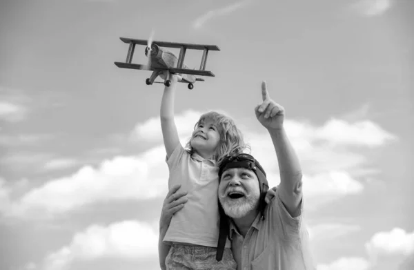 年轻的孙子和老爷爷在夏天的天空背景下玩玩具飞机 — 图库照片