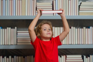 Okul kitapları ve eğitim konsepti. Öğrenci çocuk kütüphanede kitap okuyor. Çocuklar okumayı öğrenir. Öğrenci kütüphanede kitap okuyor. Ödev yapan okul çocuğu, sınıfta sıkı çalış.