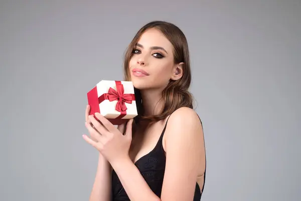 Birthday present. Sexy woman holding gift for Christmas. Sensual girl celebrate birthday with gift. Studio portrait of charming girl show gift. Holidays celebration. Gift for Womans day or Valentines
