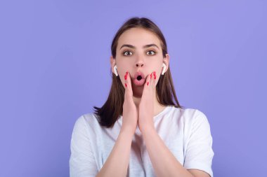 Şaşkın kadın kulaklıkla müzik dinliyor. Kulaklıklı, kablosuz kulaklıklı kız. Kulaklıkla müzik dinlemek, stüdyo. Kulaklığa kulaklık tak. Kulaklık takan bir kadın. Kablosuz kulaklık.