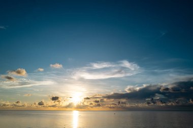 Tropikal deniz okyanusunda gün batımı ve gündoğumu bulutları. Seyahat tatili afişi. Manzara gökyüzü ve yansıma ışınları. Tropikal denizin üzerinde sahil gündoğumu. Sakin, altın gökyüzü arka planı