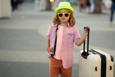 Çocuk yaz gezisine çıkıyor, valiz çantasıyla dışarı çıkıyor. Seyahat ve macera