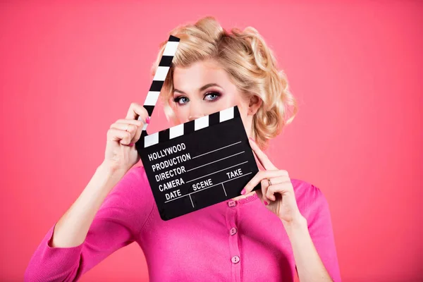 Women eyes through clapper board. Movie production clapper board, film. Clapperboard film industry. Pretty girl holding clapper board shocked hiding behind clapper board isolated on studio background