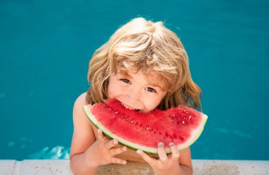Havuzda karpuz olan bir çocuk. Çocuk yüzme havuzunda eğleniyor. Çocuklar yaz tatili ve sağlıklı beslenme konsepti