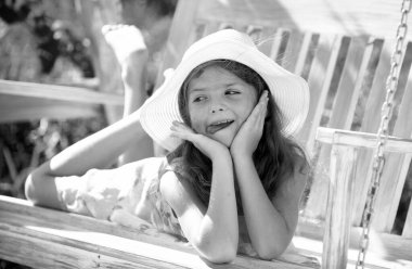 Çocuk salıncakta oynuyor. Sıcak havalarda çocuklar için sağlıklı bir yaz etkinliği. Küçük çocuklar sallanıyor. Şirin küçük kız güzel bir yaz bahçesinde salıncakta sallanıyor ve açık havada güneşli bir gün geçiriyor.