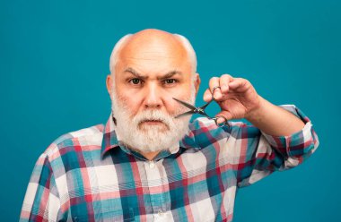 Berber makası. Orta yaşlı bir adam. Yaşlı, kel, sakallı, gri bıyıklı adamın portresi.