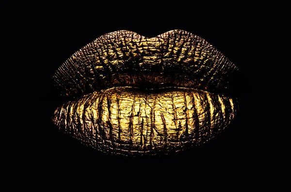 Golden lips closeup. Gold metal art lip. Beautiful makeup. Golden lip gloss on beauty female mouth, closeup. Sensual forms of woman lips