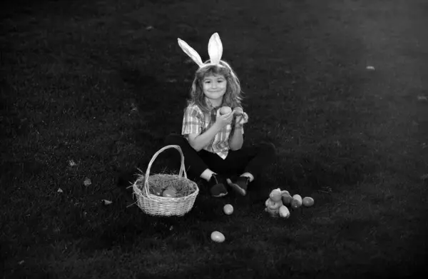 ウサギの耳を持つウサギの子供たち 庭でイースターエッグハント フィールドで遊んでいる子供の男の子 イースターエッグを狩り — ストック写真