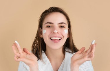 Yüz kremi süren güzel bir kadın modelin güzel portresi. Güzel yüzlü kadın, doğal ten, yüz portresi.