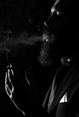 Sigara içen adam siyah stüdyoda izole halde.