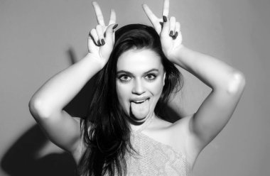 Kadın boynuz gibi parmaklarıyla komik jestler yapıyor. Çılgın komik seksi kız boynuzları gibi parmaklarıyla komik jestler yapıyor. Boynuzlarını gösteren kadın