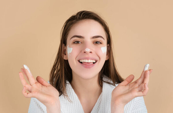 Beauty portrait of beautiful female model applying face cream. Woman with beauty face, natural skin, facial skin portrait