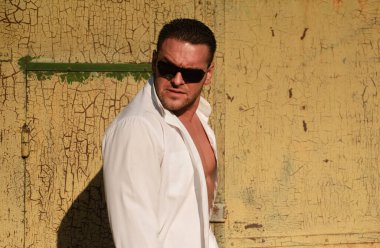 Kendine güvenen maço adam. Erkek vahşi tarzı. Beyaz gömlekli ve güneş gözlüklü çekici bir adam.