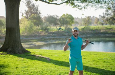 Golfçü adam güzel, güneşli yeşil golf sahasında golf oynuyor.