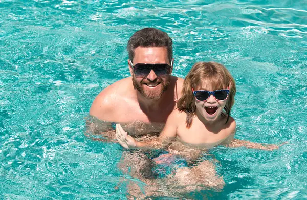 Father and son swimming in pool, summer family. Happy family in pool at summer weekend. Swimming lessons. Father son leisure