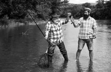 Balıkçıların arkadaşları ve ganimet alabalıkları. Baba oğul balık tutuyor. Nesiller boyu nehirde balık tutan adamlar. Mutlu heyecanlı erkek arkadaşlar