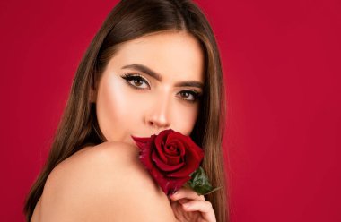Kırmızı arka planda kırmızı gül olan kadın. Dudakları rujla yakın plan. Güllü güzel kadın dudakları