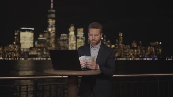 商人在夜市数钱 商人在夜市数着美国钞票 成功的生意人算数 在纽约的办公大楼上显示现金 曼哈顿夜晚的钱 — 图库视频影像