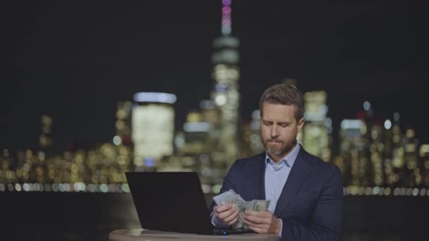 商人们在夜市的夜灯下数钱在笔记本电脑上工作 穿着西装在街上数钱的人 在纽约市算我们的美元钞票钱美国的金融和银行业 — 图库视频影像