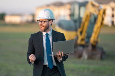 İnşaat alanında mimar. İnşaat alanında kask ve takım elbiseli mimar. İnşaatta duran kendine güvenen bir mimar. Yatırımcı ya da inşaat mühendisi. İspanyol 'un açık hava portresi