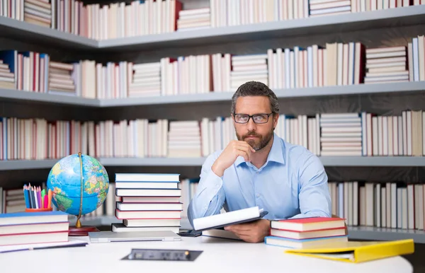 Portrait of teacher with book in library classroom. Handsome teacher in university. Teachers Day. Good school teacher. Tutor at college. Man with books in library. Knowledge and education concept