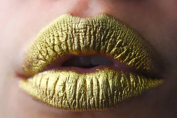 Gold lips. Gold paint on mouth. Golden lips. Luxury gold lips make-up. Golden lips with creative metallic lipstick. Gold metal lip. Sensual woman mouth, clse up, macro
