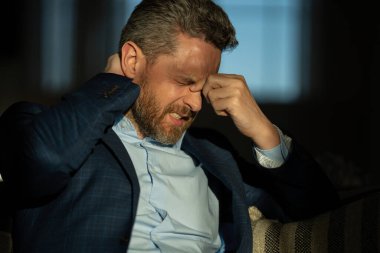 Yorgun adam acı çekiyor. Stresli bir adamın portresi ofiste baş ağrısından muzdarip. Stresli bir iş. Ağrılı bir adamın ağrıdan dolayı migreni tutar. Stresli, baş ağrısından yorgun bir adam.