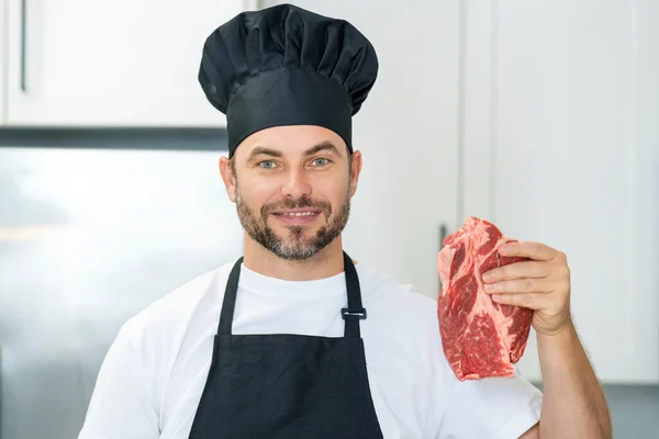 Handsome man cooking meat beef steak in kitchen. Portrait of casual man cooking with meat ingredients. Casual man preparing raw meat in kitchen. Chef cooking beef steak