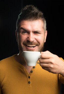 Kahve havasında olmak. Mutlu hipster sabahları kahve içiyor. Sakallı adam kahvaltıda kahve fincanıyla gülümsüyor. Kahve zamanının tadını çıkarma.