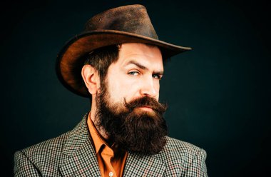 Geçmişi olan yakışıklı bir adam, siyah arka planda ciddi sakallı bir hippinin portresi.