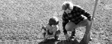 Baba oğluyla tohum ekiyor. Babası bahçedeki çocuklara yardım ediyor. Bahçıvan ailesi. Babalar Günü için pankart