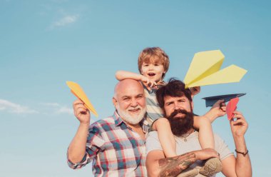 Mutlu bir babanın portresi. Oğlunu sırtında taşıyor ve yukarı bakıyor. Erkek çoklu nesil portresi. Çocukluk kavramı