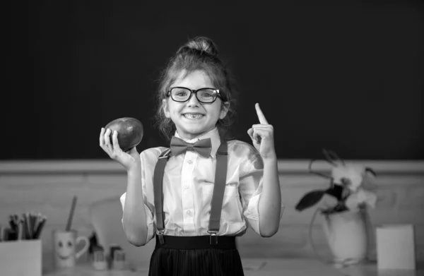 女子高生のポートレートは 黒板に指で指差す意外な表情でリンゴを持っています 学校での初日 — ストック写真