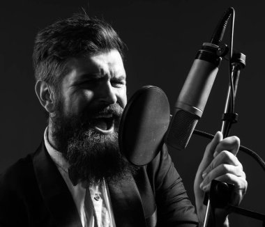 Klasik şarkıcı bir müzik stüdyosunda kayıt yaparken mikrofonla şarkı söylüyor.