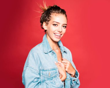 Kırmızıda izole edilmiş kot pantolonlu mutlu kız.