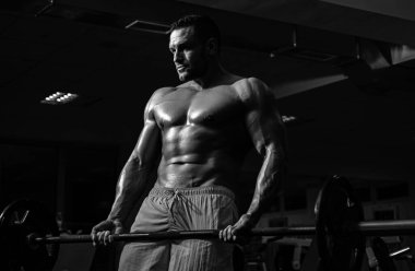 Halter kaldıran formda bir adam. Spor salonunda dambılla egzersiz yapan genç sporcunun portresi. Crossfit, spor ve sağlıklı yaşam tarzı konsepti