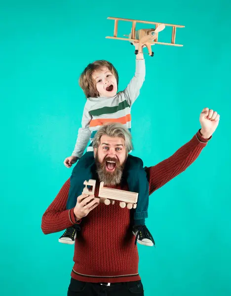 父子俩带着飞机梦想在蓝色背景下飞行的儿童飞行员 快乐的父亲骑在他的肩上仰视儿子的画像 — 图库照片