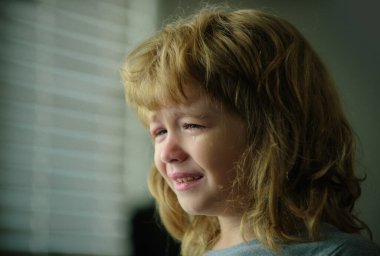 Ağlayan çocuk. Evde gözyaşı döken üzgün çocuk.