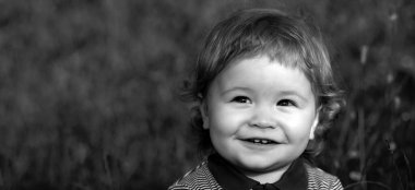 Bahar çocuğu suratlı pankart. Yaşam tarzı, bebek portresi, dışarıda, çayırda mutluluk içinde. Bebek yüzlü, yakın plan portre. Sarışın çocuk, duygusal yüz. Yeşil çim arka plandaki çocuklar