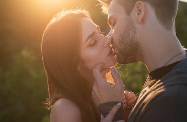 Şehvetli bir öpücük. Genç çift öpüşüyor ve sevişiyor. Aşıkları öpüyor. Gün batımına karşı öpüşmeyi bekleyen güzel bir çiftin portresi.