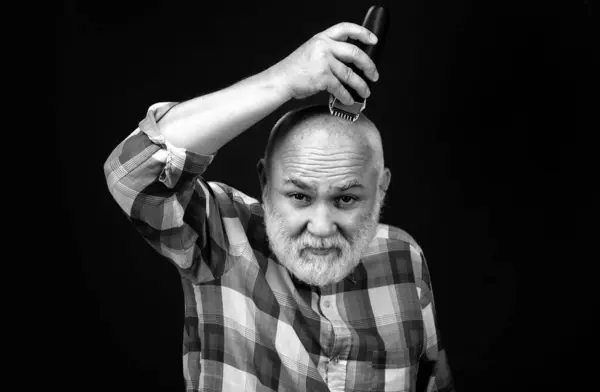 Old man with hair clipper isolated on black. Bald man hairclipper, Mature baldness and hair loss concept