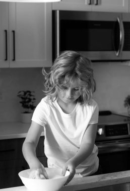 Çocuk bulaşıkları süngerle yıkıyor. Temizlik malzemeleri. Temizliğe yardım et. Oda servisi görevleri. Çocuk bulaşıkları yıkıyor. Mutfakta lavabonun yanında bulaşık yıkayan tatlı bir çocuk.