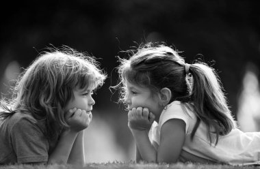 Erkek ve kız kardeş parkta eğleniyor, iki neşeli çocuk yeşil çimlere uzanıyor. Mutlu aile aşkı ve mutluluk kavramı