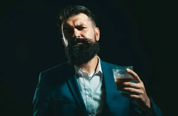 Fashion style concept. Tasting and degustation concept. Barman or Bartender serves cognac. Bearded handsome man holding glass of whiskey